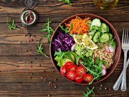 A colorful plate of healthy food including fresh vegetables, grilled chicken, brown rice, and a glass of lemon water, representing a balanced diet in a weight management program.