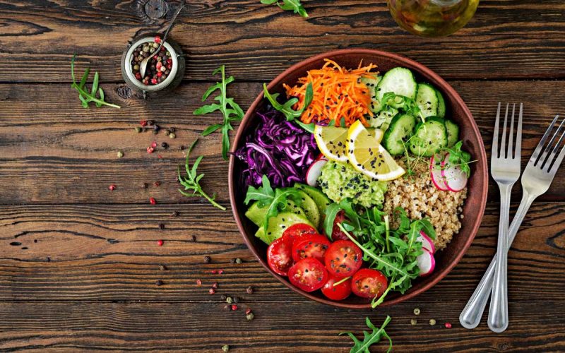 A colorful plate of healthy food including fresh vegetables, grilled chicken, brown rice, and a glass of lemon water, representing a balanced diet in a weight management program.